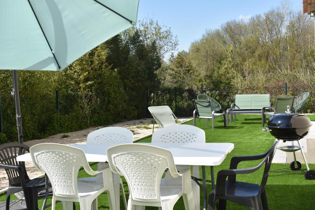 un groupe de tables et de chaises blanches avec un gril dans l'établissement La Villa du Sud, Arles Camargue, à Arles