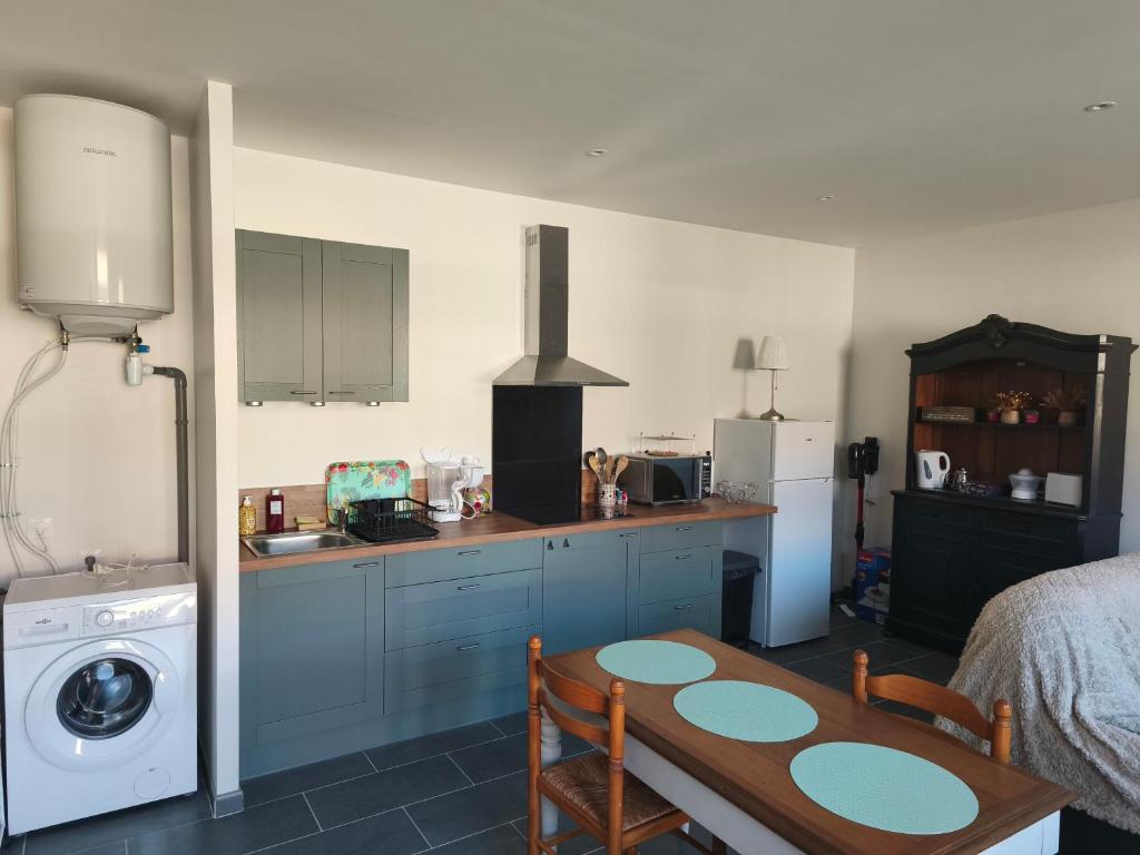 La cuisine est équipée de placards bleus, d'une table et d'un réfrigérateur. dans l'établissement Les gîtes de Pierre, à Saint-Christ-Briost