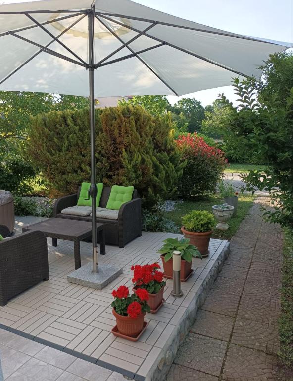 a patio with an umbrella and chairs and plants at Guesthouse Adriana Cottages in Labin