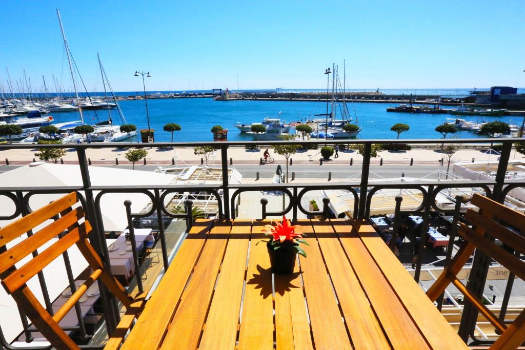 un banco de madera en un balcón con vistas al puerto en Apartamentos La Torre, en Cambrils