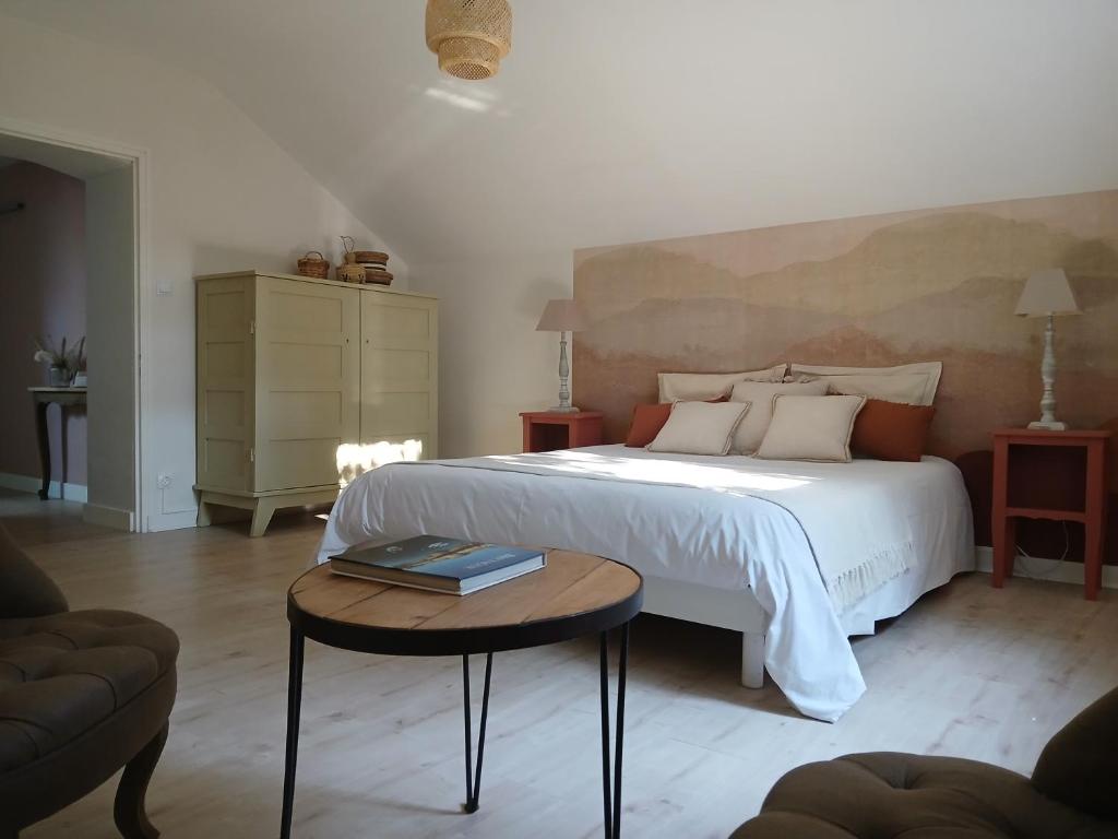 une chambre avec un grand lit blanc et une table dans l'établissement L' Arbre à noisettes, à Ploërmel
