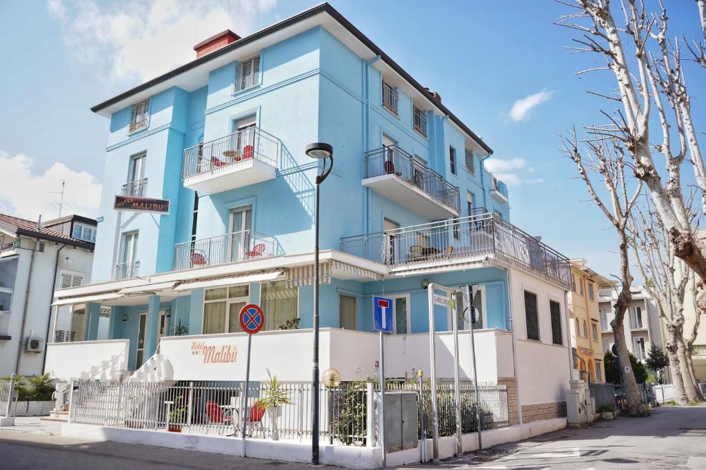 un bâtiment bleu et blanc au bord d'une rue dans l'établissement Hotel Malibù Mare, à Rimini