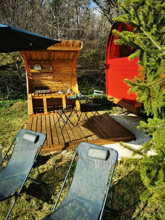une terrasse en bois avec deux chaises et un sauna dans l'établissement La roulotte des nuits étoilées du moulin, à Sainte-Orse