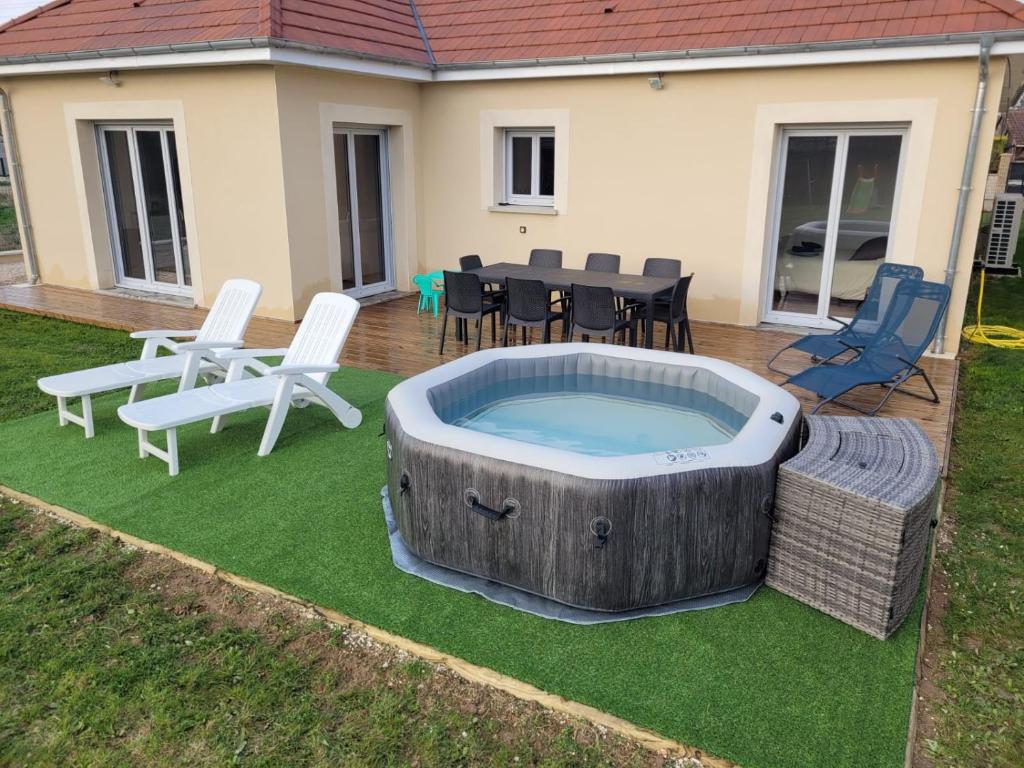 einen Whirlpool im Garten mit Stühlen und einem Tisch in der Unterkunft Villa Noyers, 1 heure de Paris à la campagne in Serbonnes