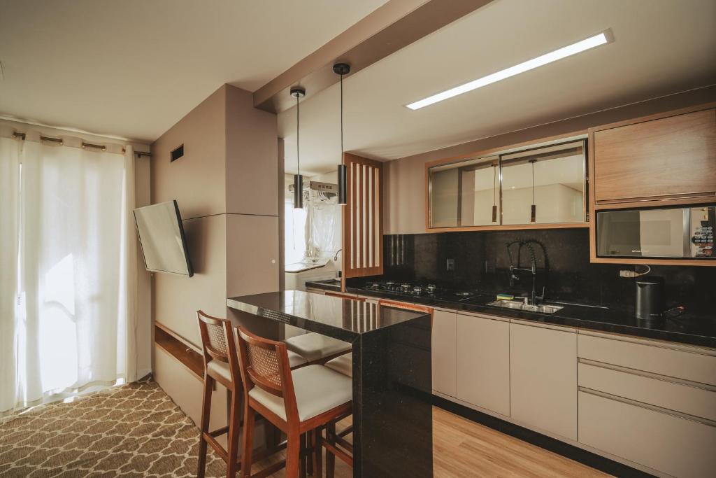 a kitchen with a black counter and wooden cabinets at Apartamento moderno na Pedra Branca in Palhoça