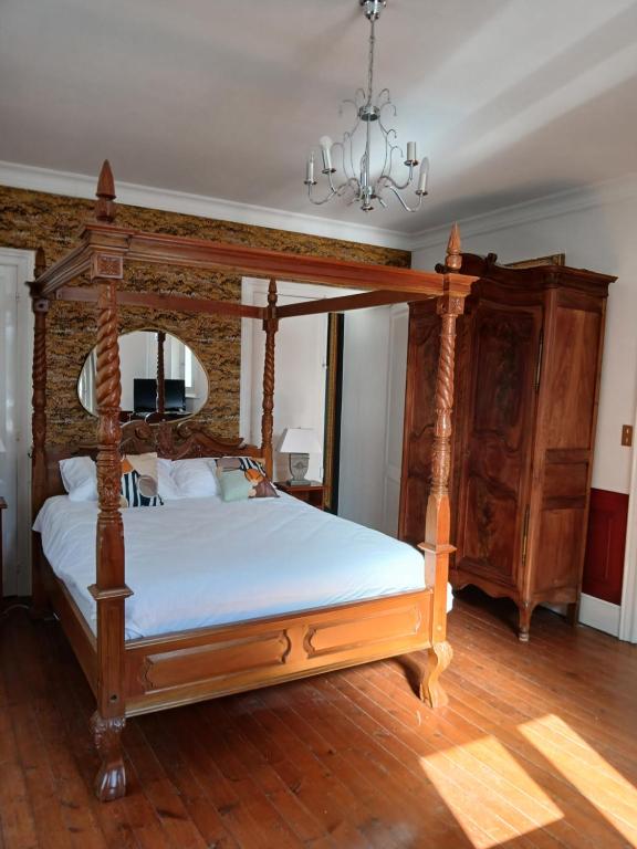 - une chambre avec un lit à baldaquin en bois et un lustre dans l'établissement spa suite Calèche, au chateau au milieu d un bois en baie de somme, à Mons-Boubert