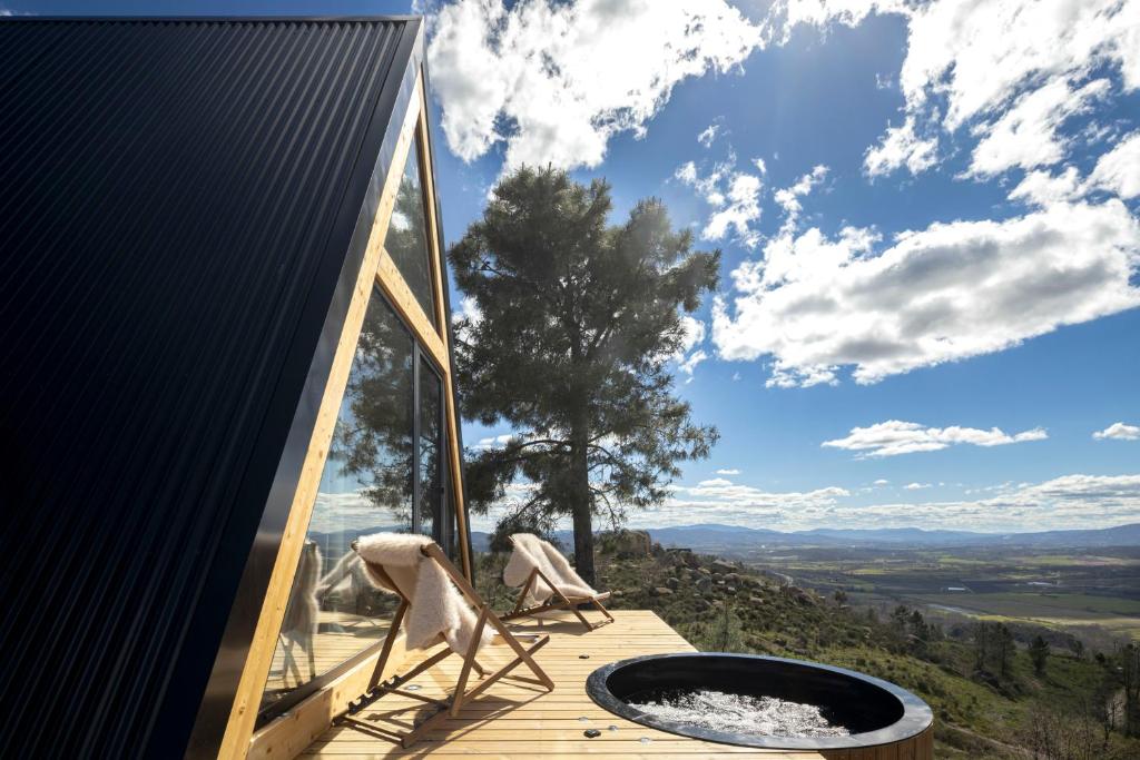 a room with a hot tub and chairs on a deck at TheVagar - Glamping Mountain Shelters in Belmonte