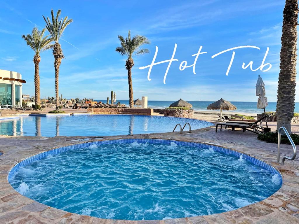 a swimming pool with palm trees and the words hot tub at Beachfront Condo with Pools & Beach #202 in Playa Encanto