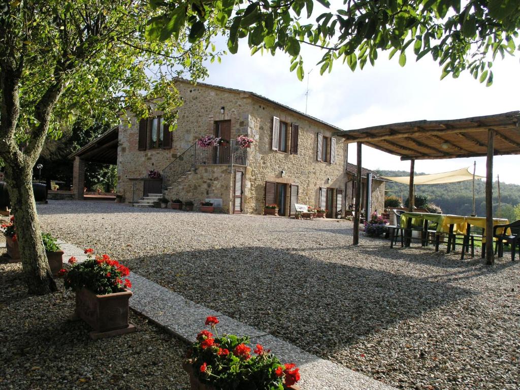 uma casa de pedra com mesas, cadeiras e flores em San Fedele Alloggi em Siena
