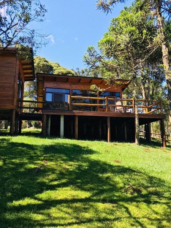 a house with a large deck in the grass at Cabana Fruta Fina - Urubici/SC in Grão Pará