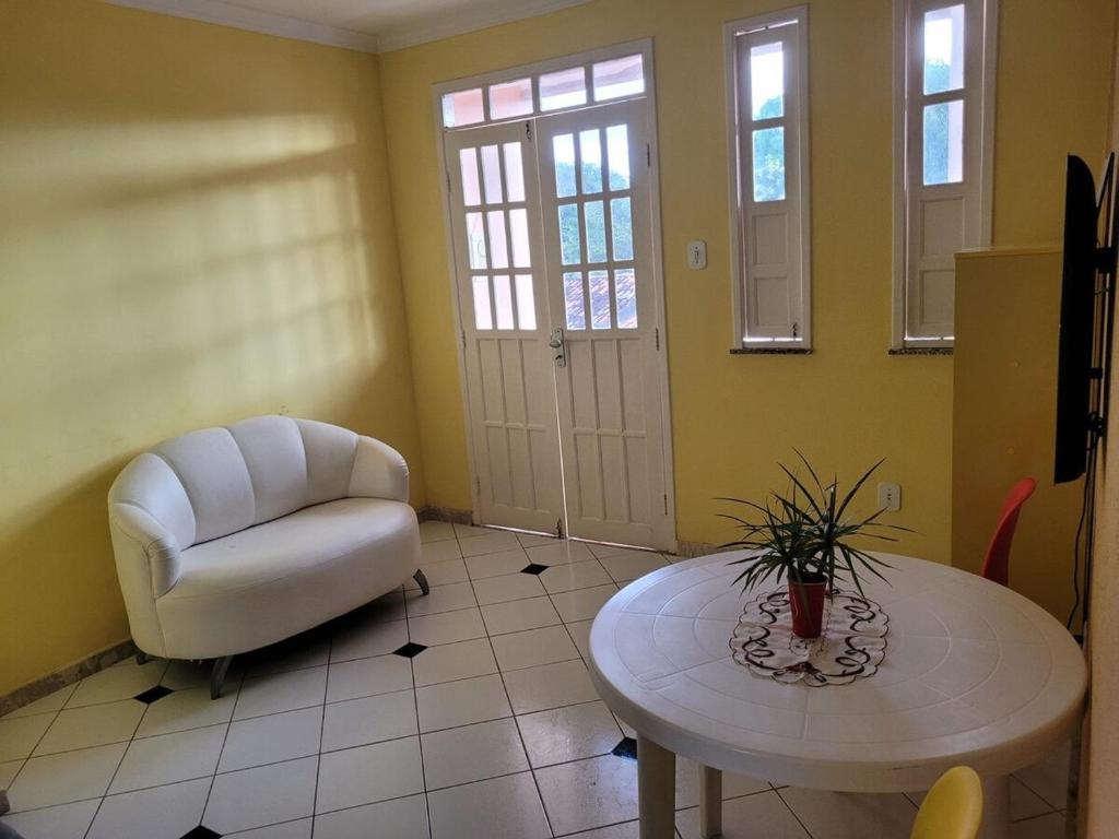 a living room with a white chair and a table at Cacha Pregos Vera Cruz - BA in Vera Cruz de Itaparica
