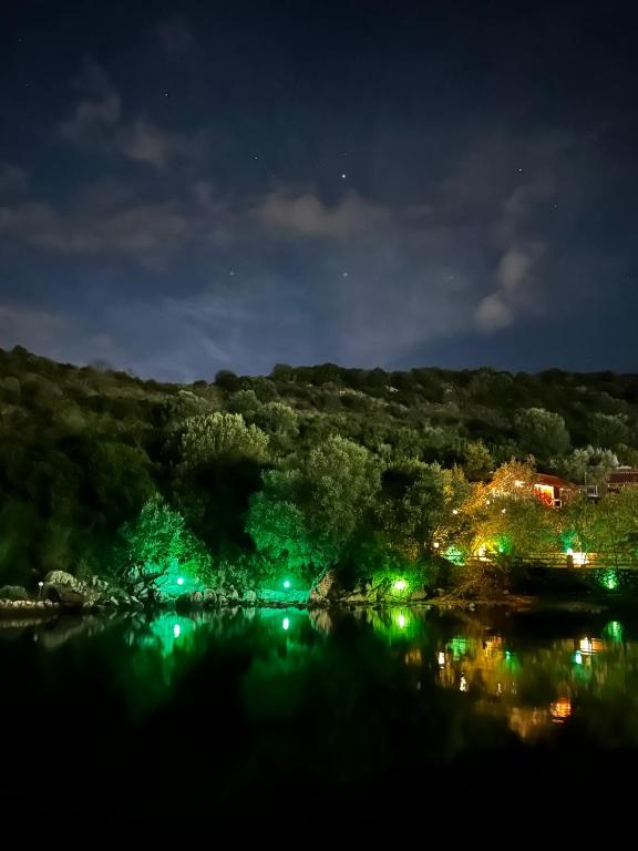 a view of a lake at night with green lights at The Mussel House in Ksamil