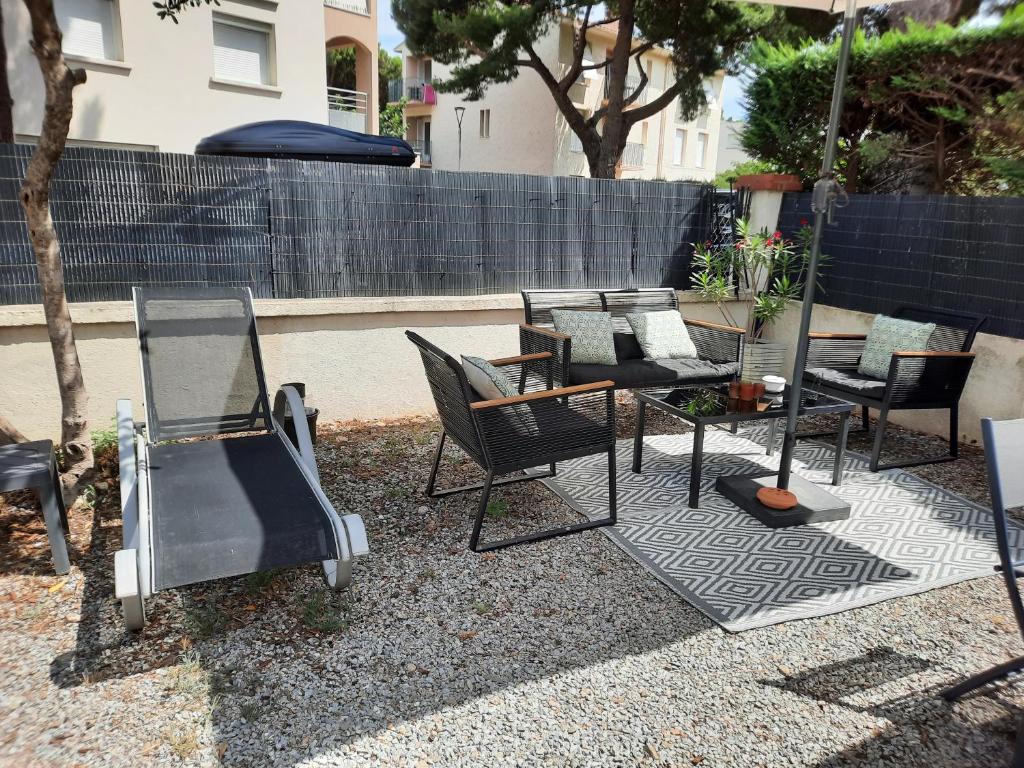 un groupe de chaises et de tables sur une terrasse dans l'établissement Appartement avec jardin 1 minute à pied la plage, à Plage dʼArgelès