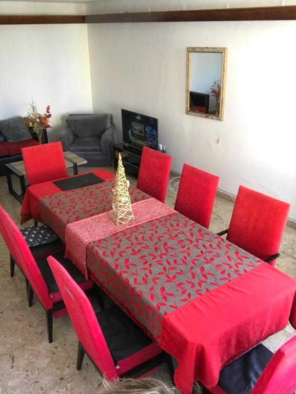 a red dining room table with red chairs and a christmas tree on it at Edelweiss, amplio departamento in Comodoro Rivadavia