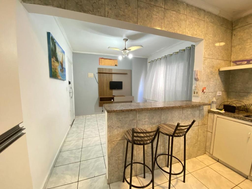 una cocina con dos taburetes en un mostrador en Apto 2min da praia Ocian! Perto da Estatua Netuno!, en Samaritá