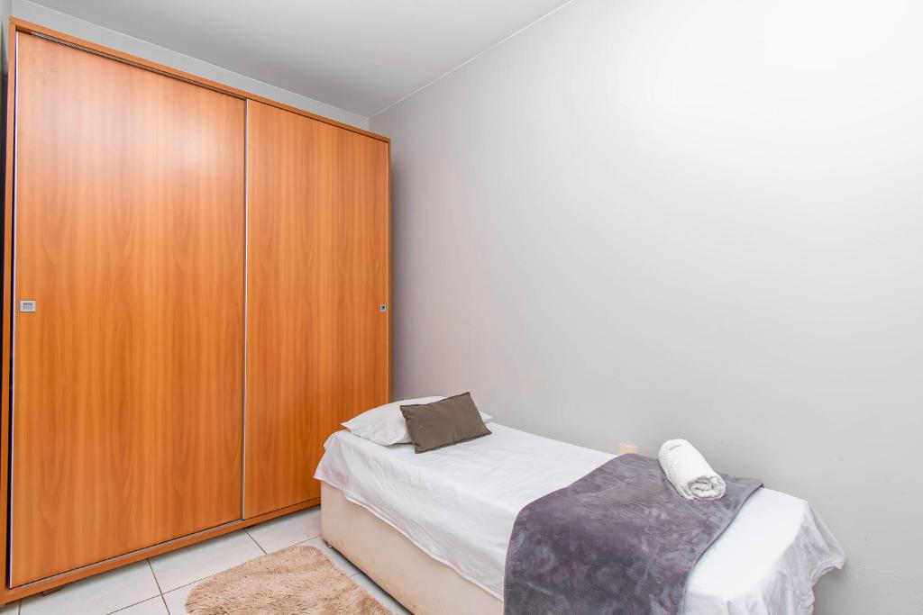 a bedroom with a bed and a wooden cabinet at Centro de BSB - quarto duplo in Brasilia