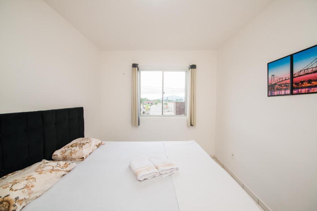 Una habitación blanca con una cama y una ventana en Apartamento próximo a BR 101 ideal para viajantes, en Palhoça