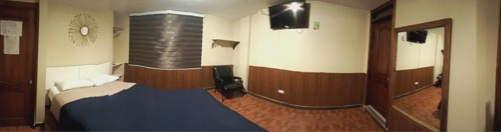 a small room with a bed and a mirror at Hotel Guajacum Riobamba in Riobamba