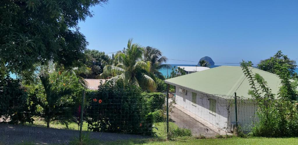 a fence in front of a house with a building at Suite Caraïbes, vue mer in Le Diamant