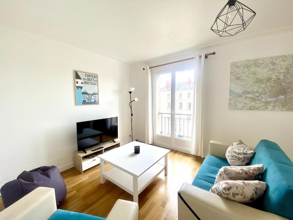 un salon avec un canapé bleu et une table dans l'établissement NaonedLoft au Coeur de la Ville, à Nantes