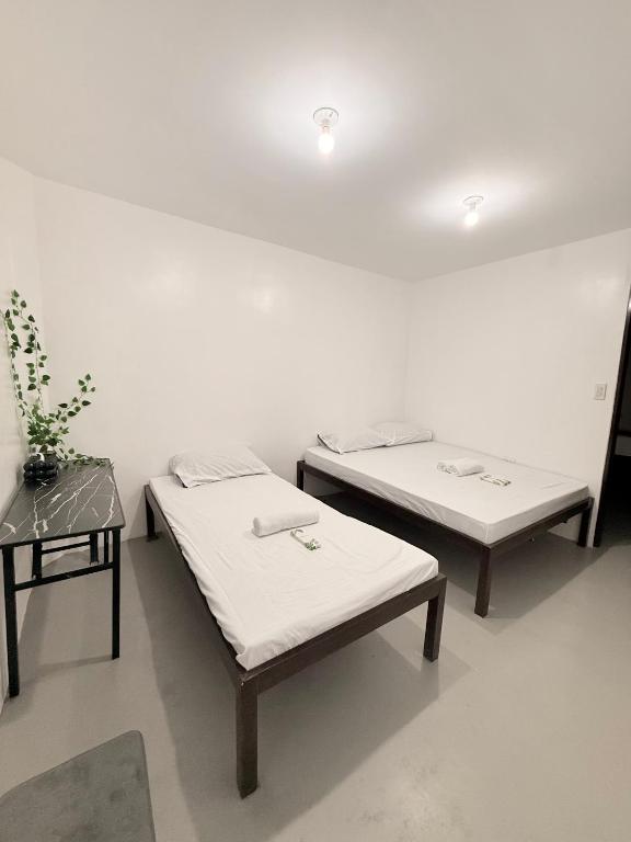 two beds in a room next to a table at Inn Convenience in Coron