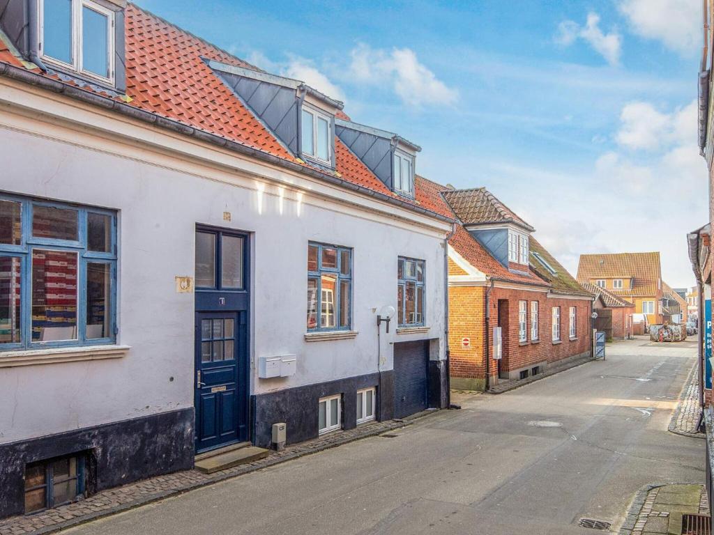 a white building with a blue door on a street at 2 person holiday home in Ringkøbing in Ringkøbing