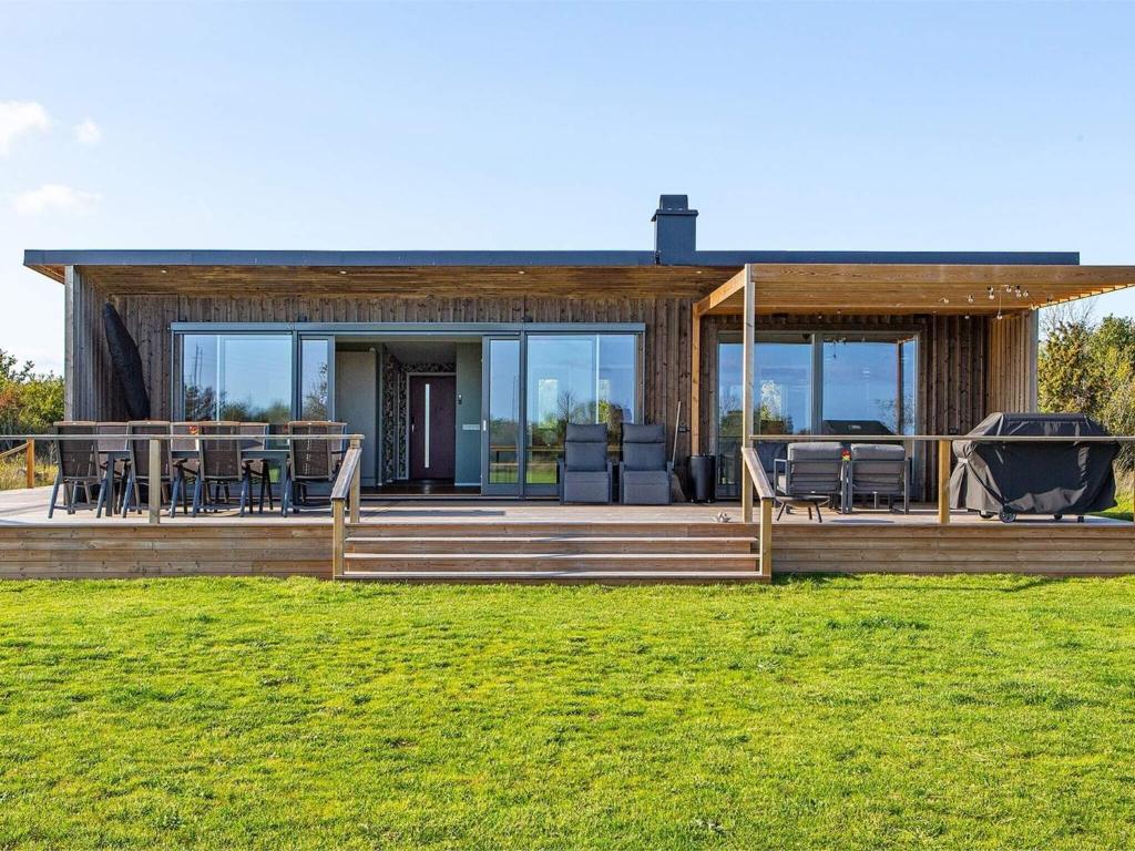 a house with a large deck with chairs and tables at 5 star holiday home in Löttorp in Löttorp