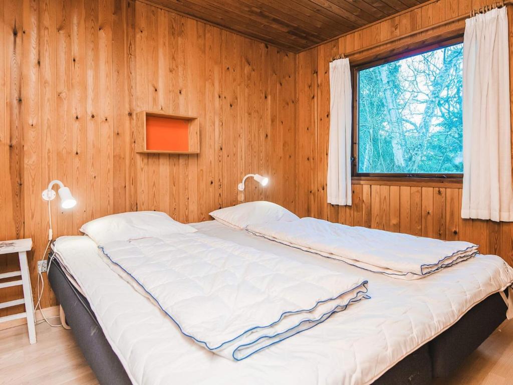 a bed in a wooden room with a window at 6 person holiday home in Fanø in Fanø