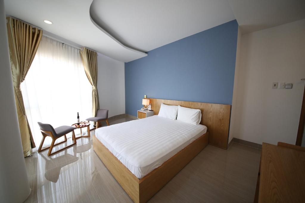 a bedroom with a bed and a blue wall at Sailing Hotel Phú Quốc in Phú Quốc