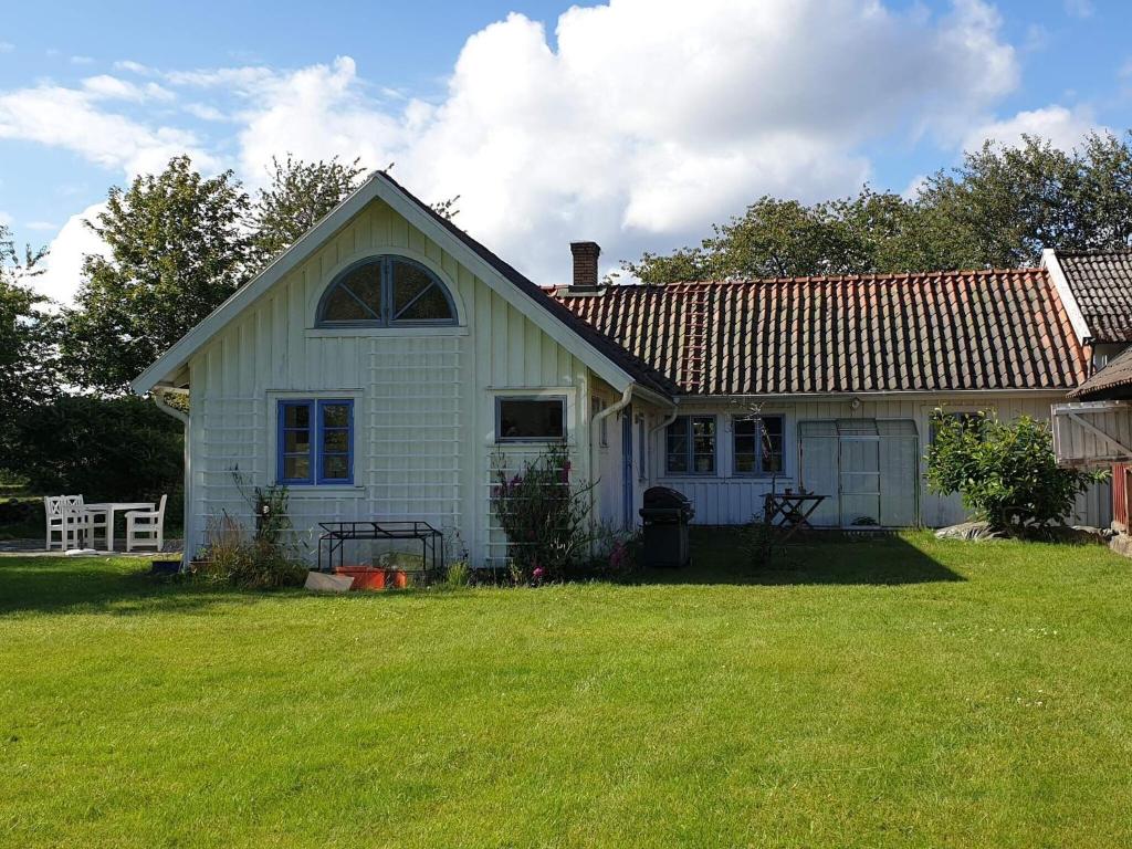 a small white house with a grass yard at 4 star holiday home in Åsa in Åsa