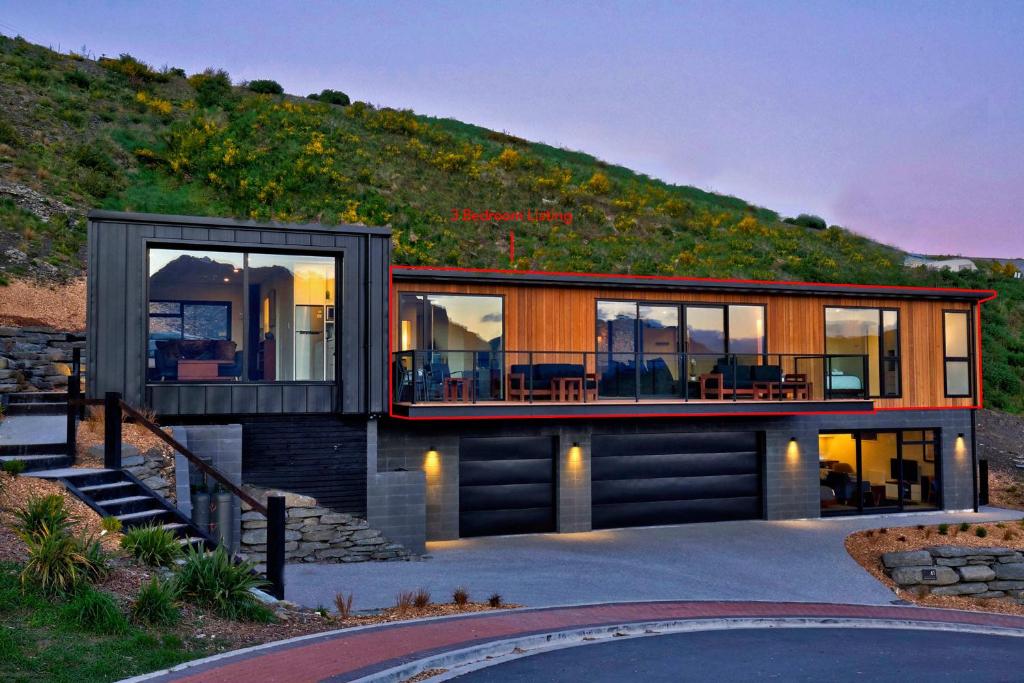 a house on a hill with glass doors at Mountain Lake Vista 3 Bedroom in Queenstown