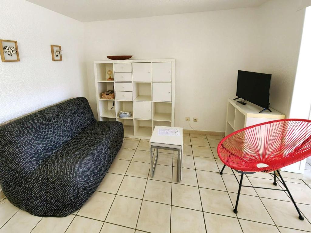 un salon avec un canapé et une chaise dans l'établissement Joli T2 rez-de-jardin avec piscine et parking - FR-1-607-211, au Cap d'Agde