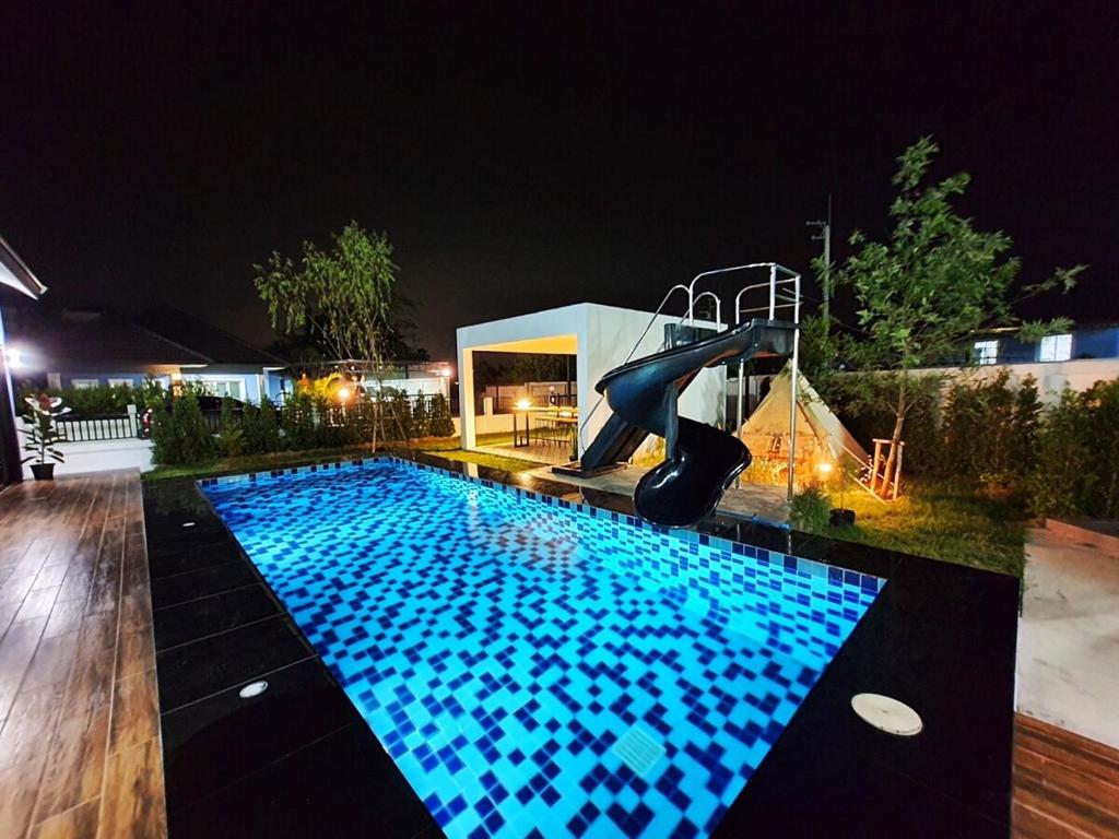 une piscine la nuit avec un toboggan dans l'établissement Morning Glory Pool Villa Chaam-Huahin, à Sathani Huai Sai Tai