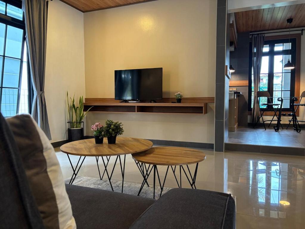 ein Wohnzimmer mit 2 Tischen und einem TV in der Unterkunft hillcure villa kota bunga puncak by citrus house in Cikundul