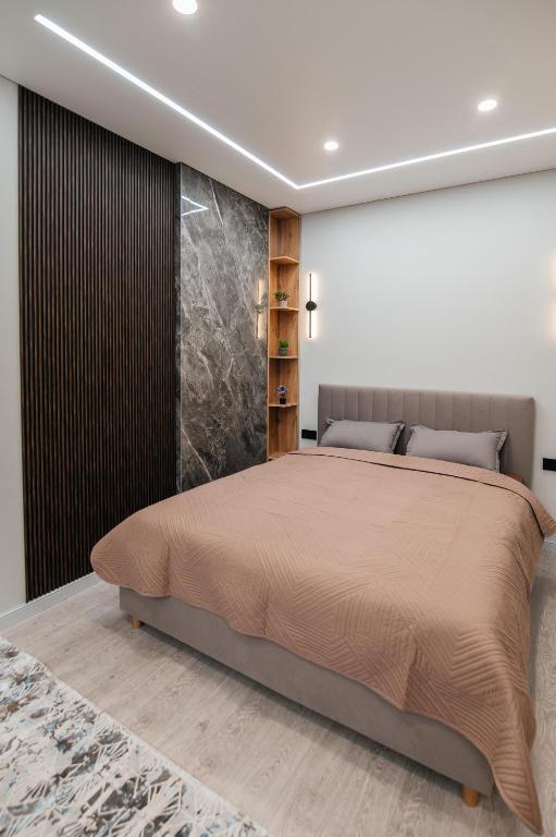 a bedroom with a large bed and a stone wall at ЖК Sun city in Oral