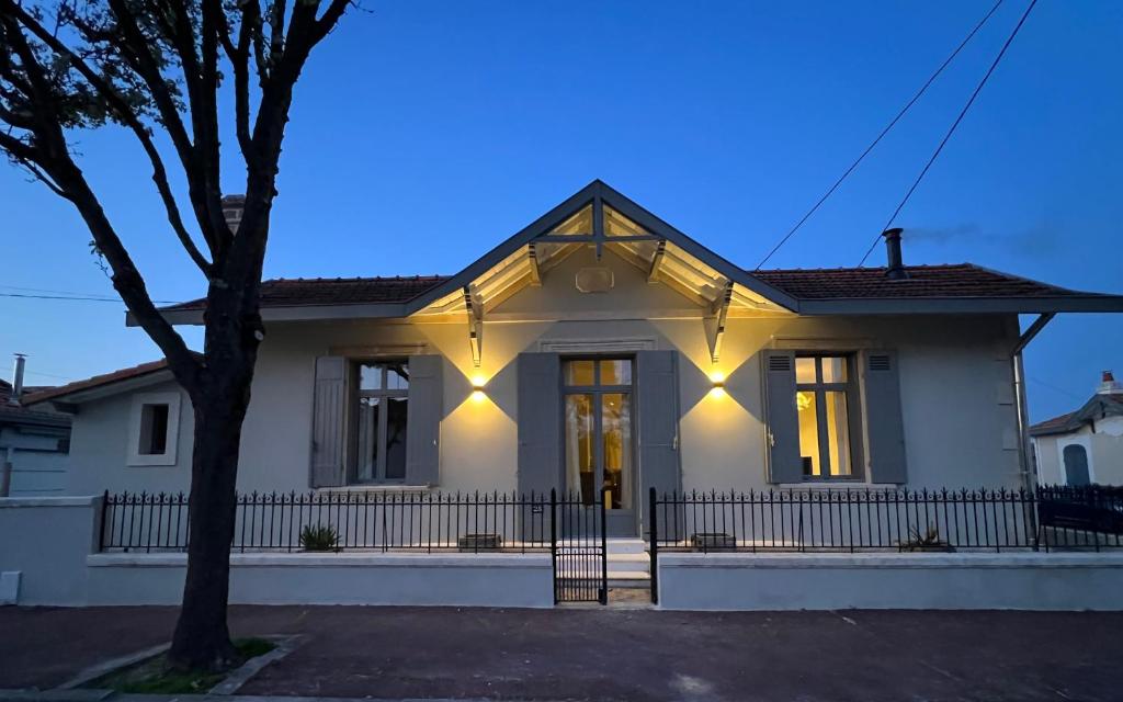 une maison blanche avec des lumières à l'avant dans l'établissement Luxe et Charme - L'Alcôve - Plage à pieds - Meublé de tourisme 4 étoiles -, à Arcachon
