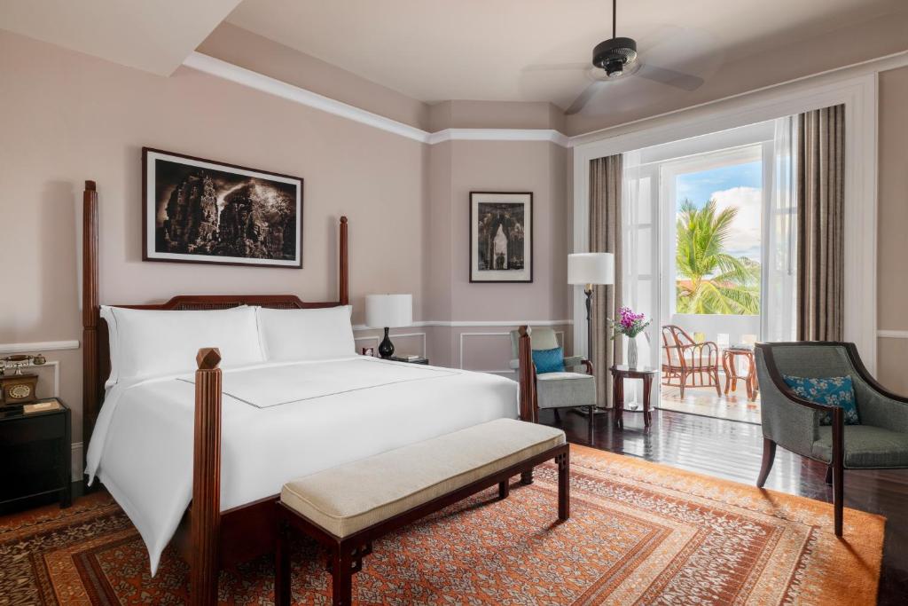 a bedroom with a bed and a living room at Raffles Grand Hotel d'Angkor in Siem Reap