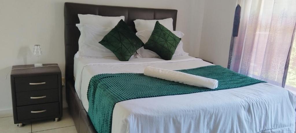 Cama con manta y almohadas verdes y blancas en Southside Nest, en Johannesburgo