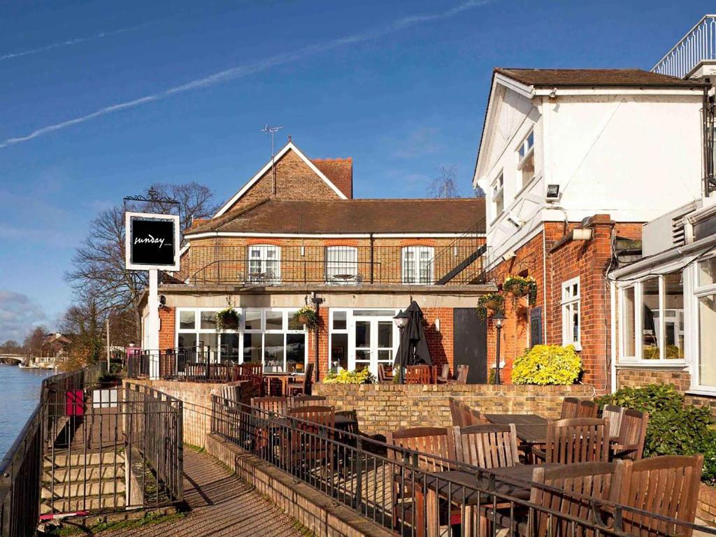a large brick building with tables and chairs next to the water at Sunday London Staines-upon-Thames Heathrow T5 in Staines