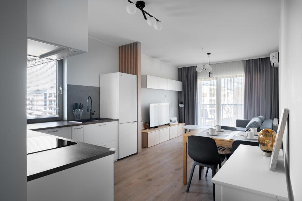 a kitchen with white cabinets and a dining table at Apartament Moon by Rentoom Aparthotels in Toruń