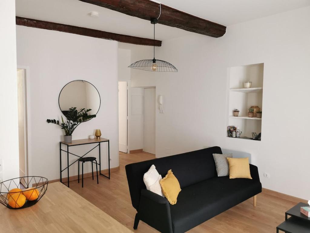 un salon avec un canapé noir et une table dans l'établissement Appartement 2 chambres-Vue imprenable sur la Cathédrale-Wifi, à Béziers