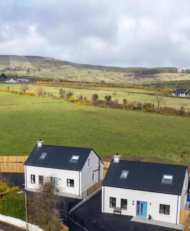 an aerial view of a white house and a field at Crann Darach Cottages in Artikelly