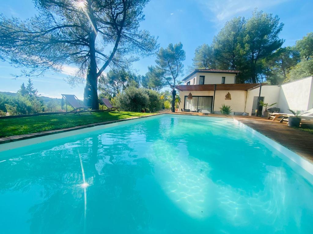 une piscine bleue devant une maison dans l'établissement Le Secret des Pins, à Pernes-les-Fontaines