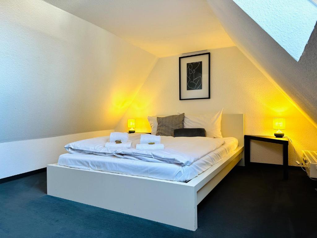 a bedroom with a large white bed with two lamps at Galerie-Dachstudio- Ruhig & kompakt-Waschmaschine- WLAN- Parkplatz in Wolfsburg