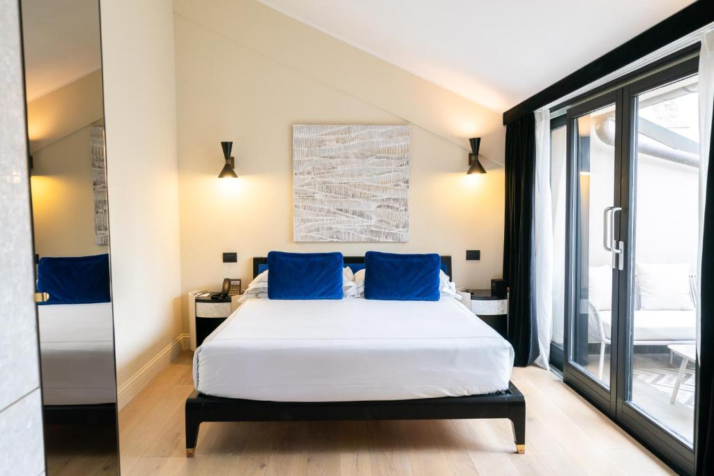 a bedroom with a bed with blue pillows at Roma Luxus Hotel in Rome