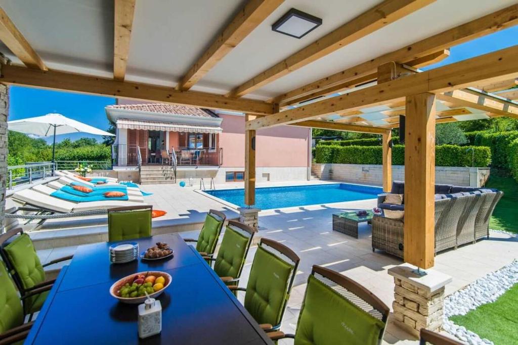 a patio with a blue table and chairs and a pool at Villa Maklavun by Kompas Villas in Kanfanar