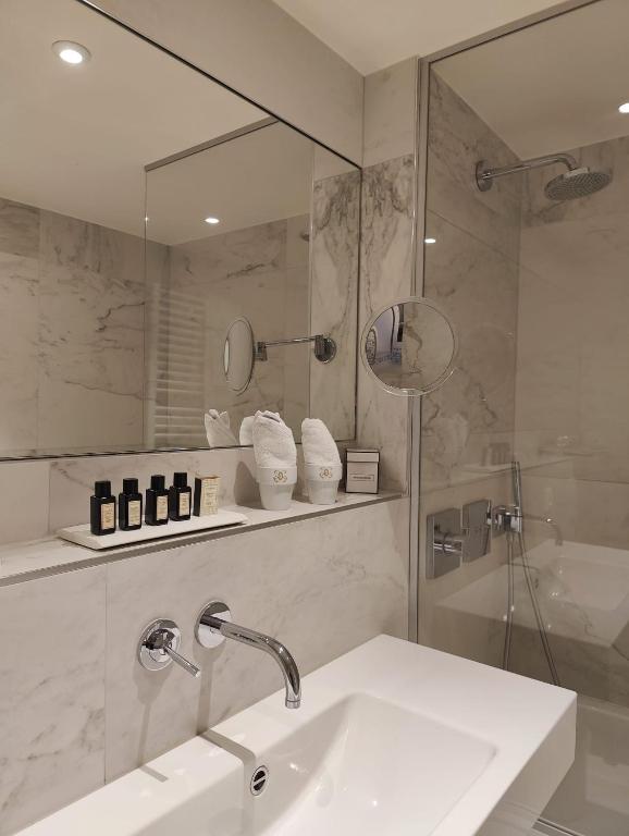 uma casa de banho com um lavatório, um chuveiro e um espelho. em Hotel De Orangerie by CW Hotel Collection em Bruges