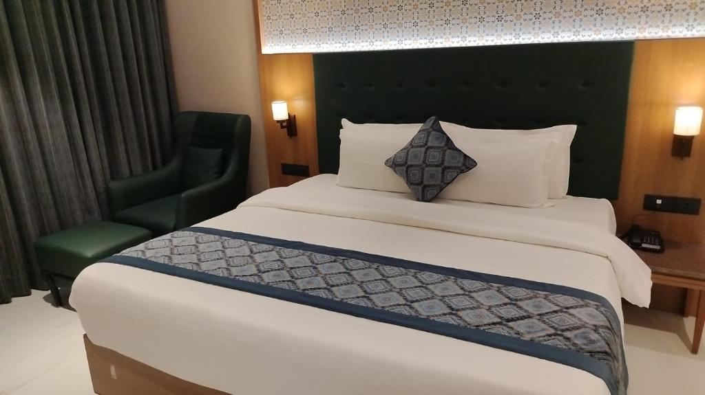 a bedroom with a large bed and a green chair at Hotel Surya, Kaiser Palace in Varanasi