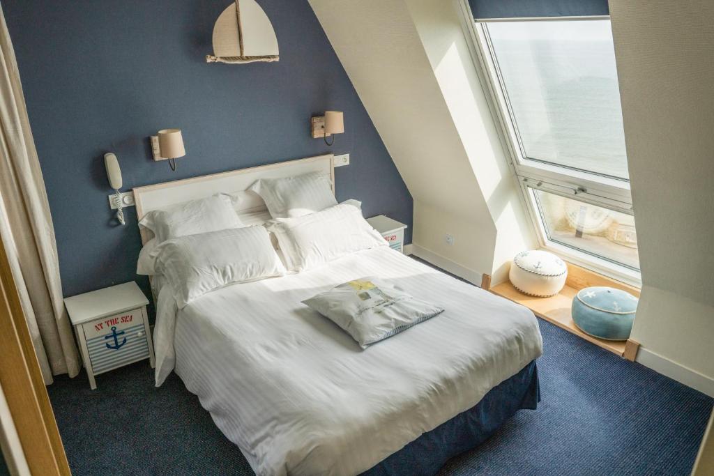 a bedroom with a large bed and a window at Logis Hotel Du Casino Restaurant Le Mathelia in Vierville-sur-Mer
