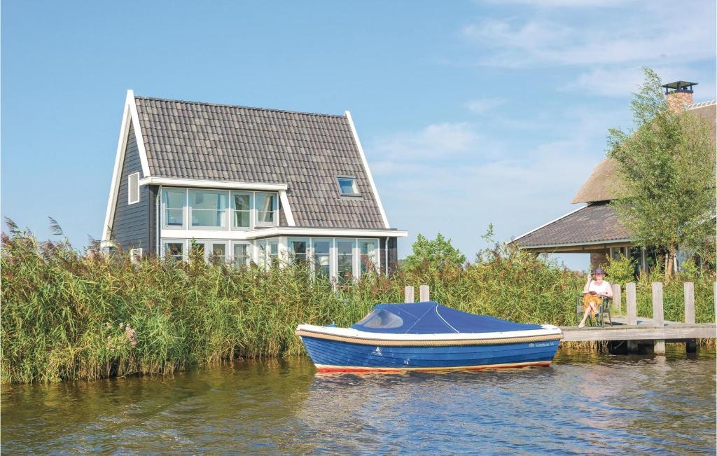 a blue boat on the water in front of a house at Bodelaeke-Wieden 4P in Giethoorn